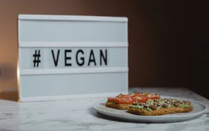 © Tima Miroshnichenko_Pexels Teller mit Broten, dahinter Aufschrift vegan