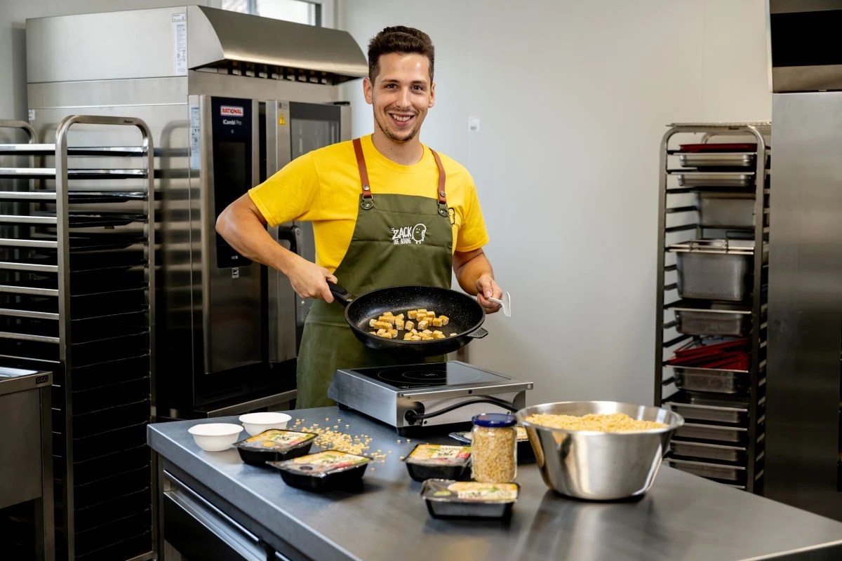 Unternehmensgründer Hannes Weichhart präsentiert frisch gebratene Tempeh-Würfel in einer Pfanne