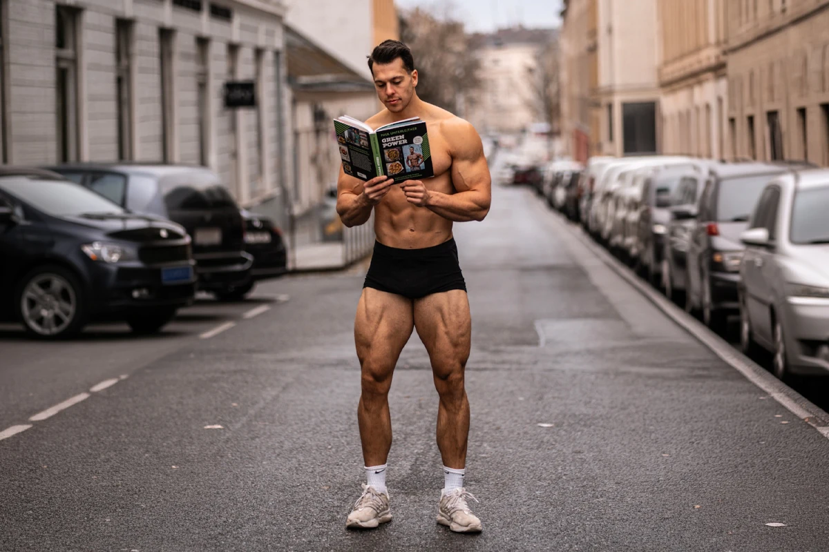 Paul Unterleitner steht auf einer Straße in Wien und liest in seinem Kochbuch "Green Power"