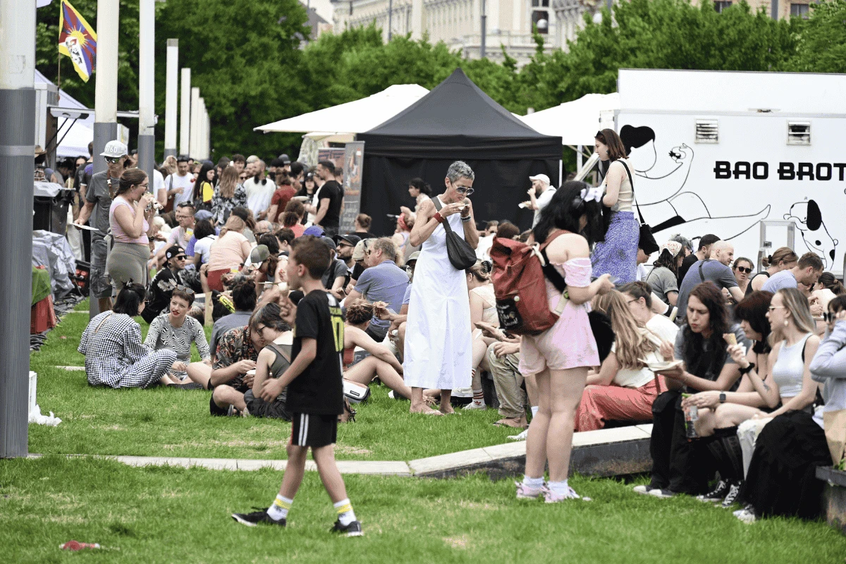 Menschen sitzen auf einer Wiese neben dem Wiener Museumsquartier und essen Streetfood.