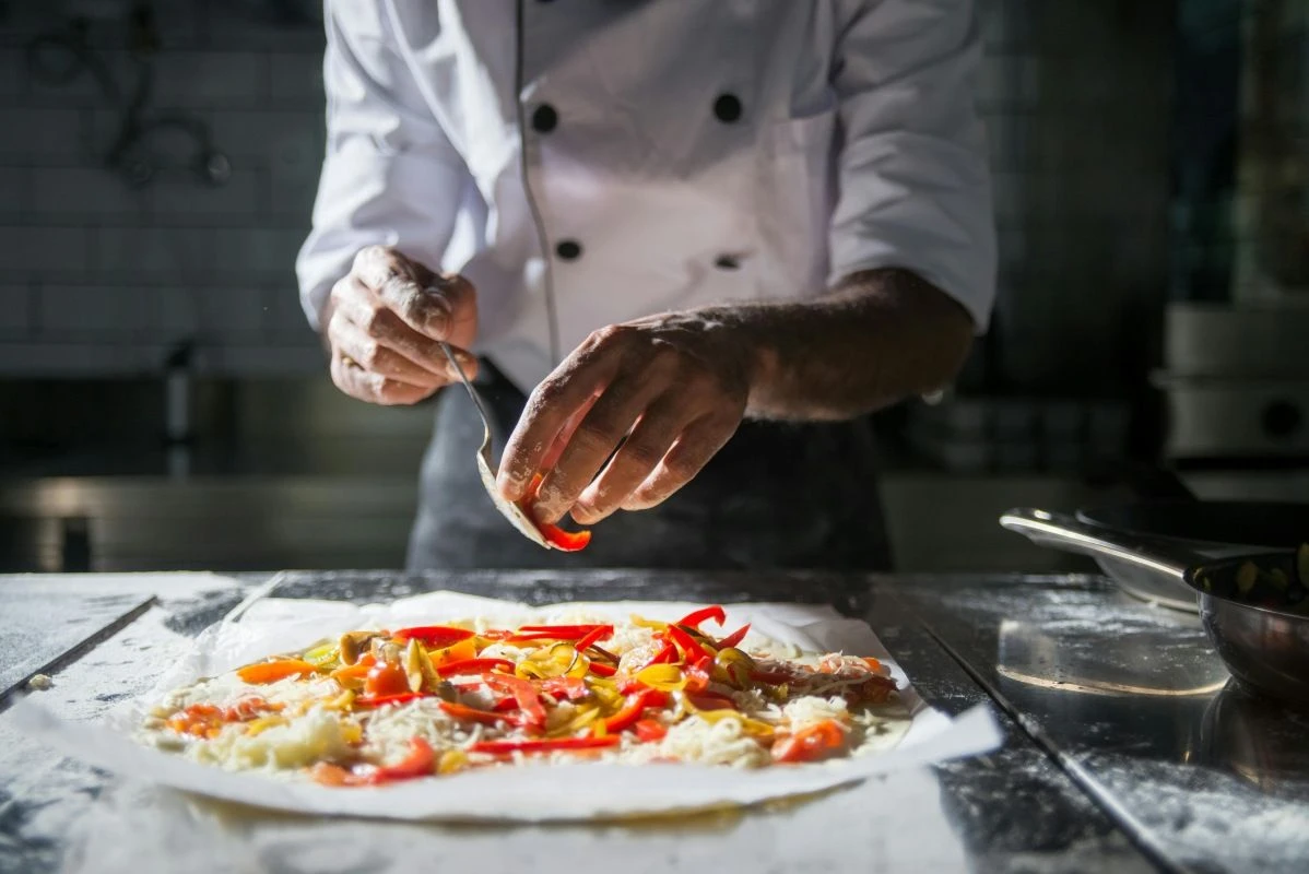 Koch bei der Zubereitung einer Pizza