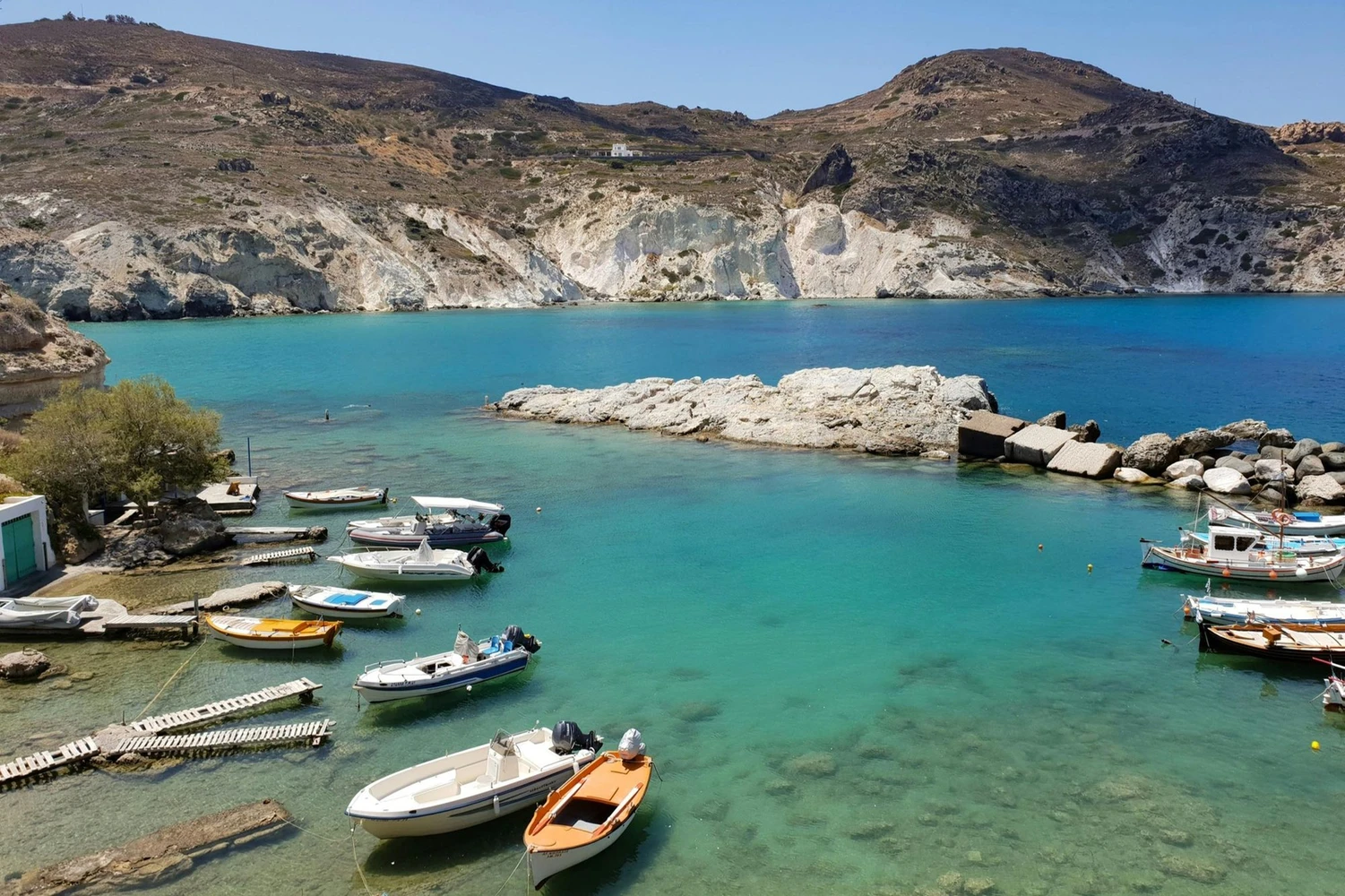 kleiner Hafen mit kleinen Booten, türkisblaues Meer und eine Insel im Hintergrund